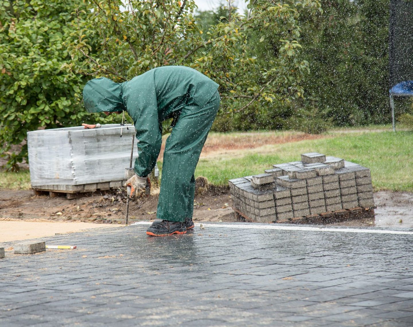 Pflasterarbeiten bei Regen auf einer frisch verlegten Fläche